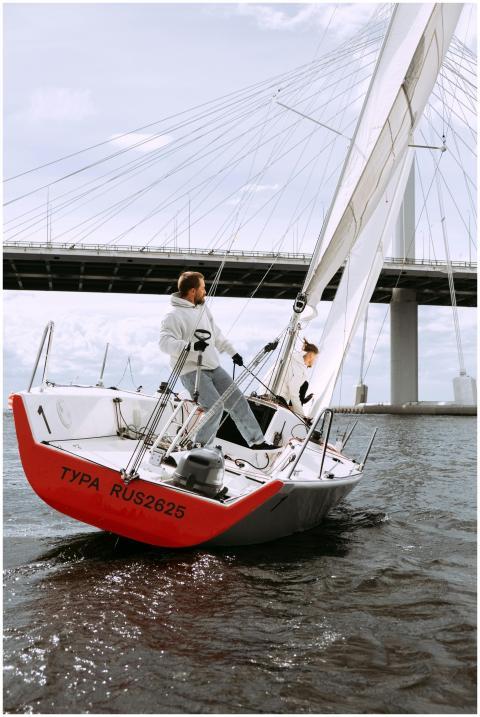 Two sailors skillfully navigate a yacht under a br