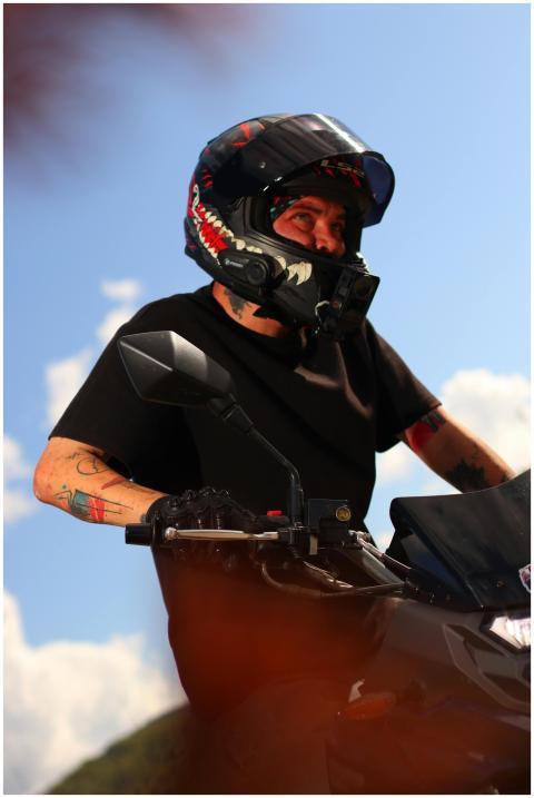 Motorcyclist wearing a shark-themed helmet riding