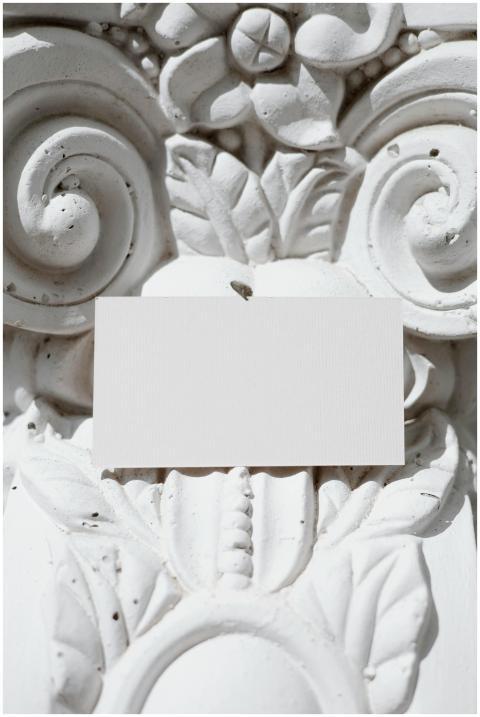 A blank card hangs on an ornate white stone wall,