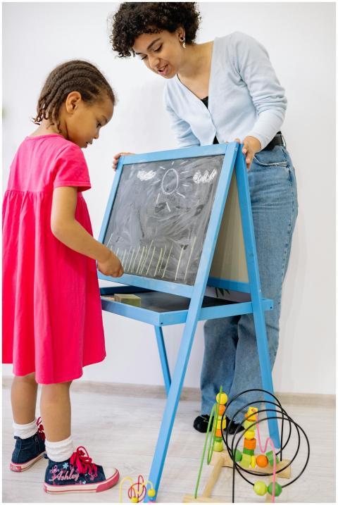 A young girl and teacher enjoy a creative learning