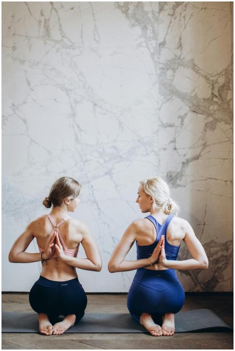 Two women in activewear practicing yoga in a seren