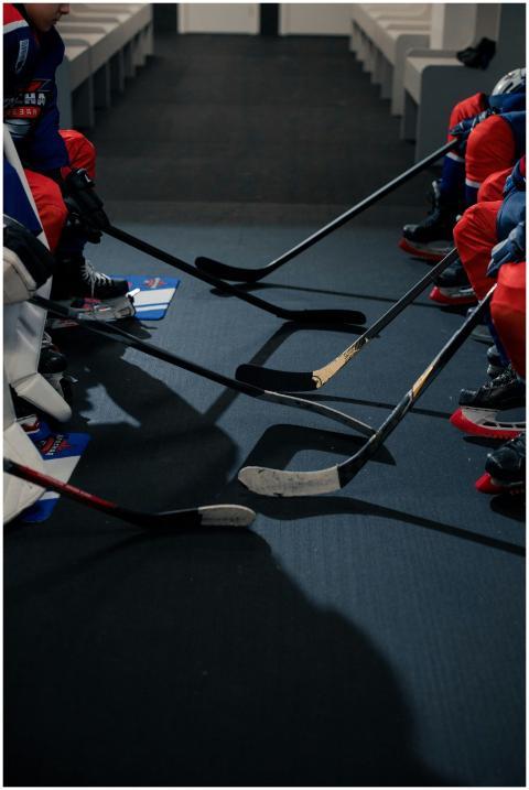 Hockey players' sticks aligned on the floor in a l