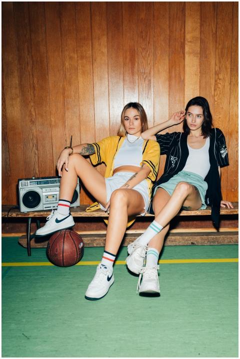 Two stylish women seated in a gym, exuding modern