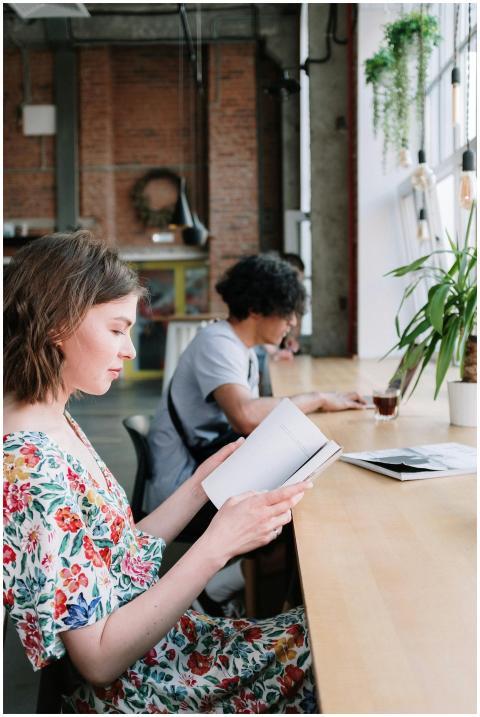Two individuals reading at a wooden table in a mod