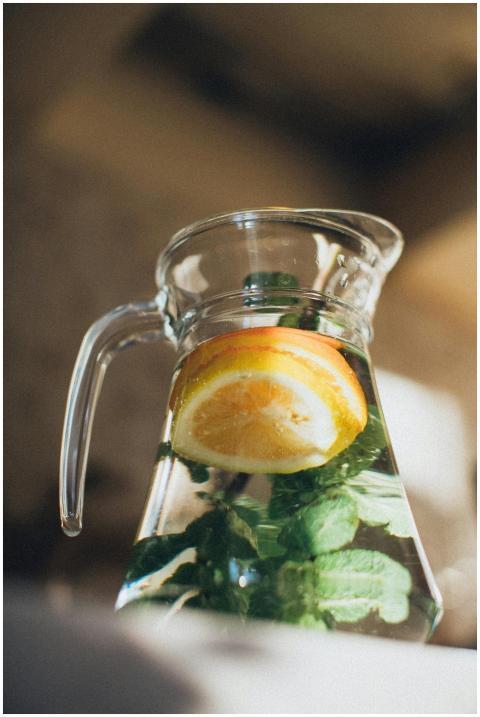 A pitcher of fresh lemon water with mint leaves, c