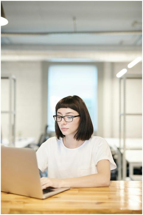 Focused young woman in glasses working on a laptop