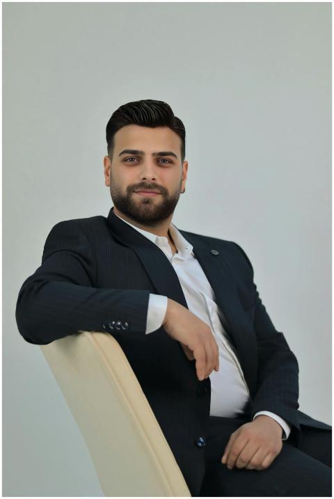 Young man in a formal suit confidently seated, exu