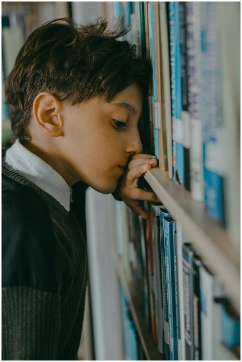 A young boy in a library, appearing thoughtful and