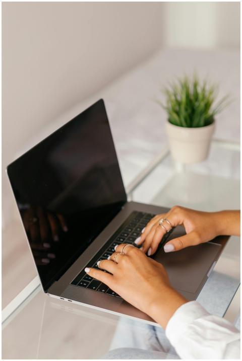 Close-up of woman's hands typing on a laptop at a