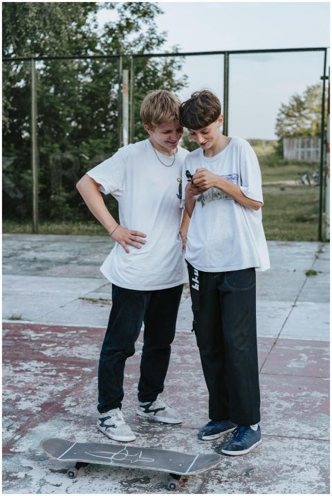 Two teenage boys smiling and checking their phone