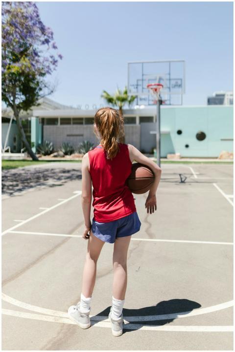 A child holding a basketball on an outdoor court,