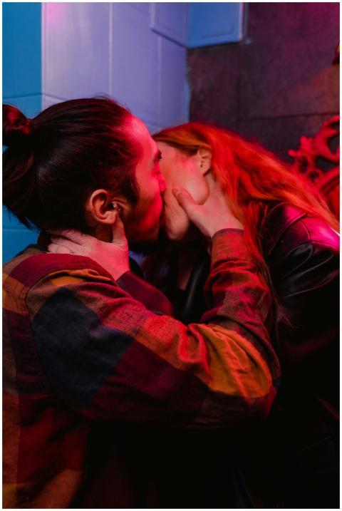 A couple shares a passionate kiss under mood light