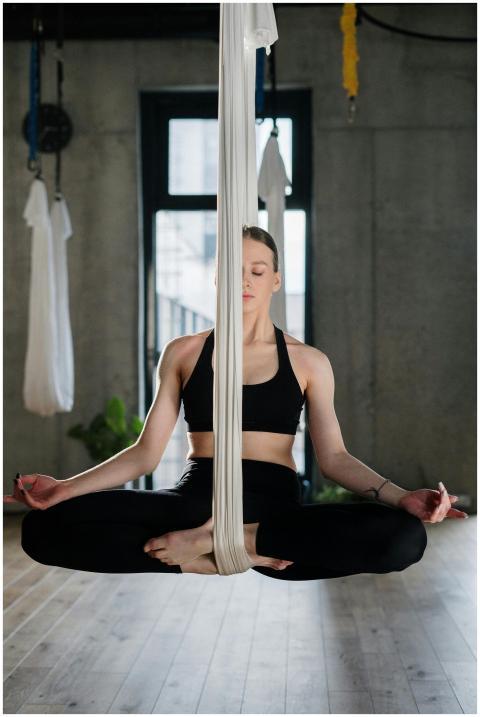A woman in a yoga studio performing aerial yoga in