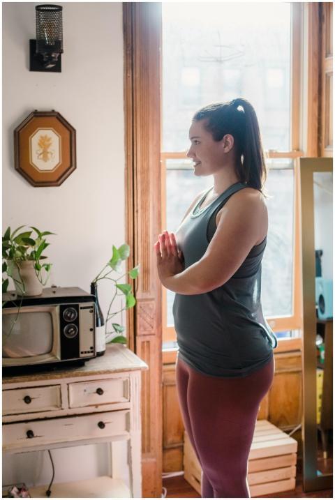 A woman practicing yoga at home by the window with