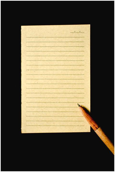 A vertical shot of lined paper and a wooden pen on
