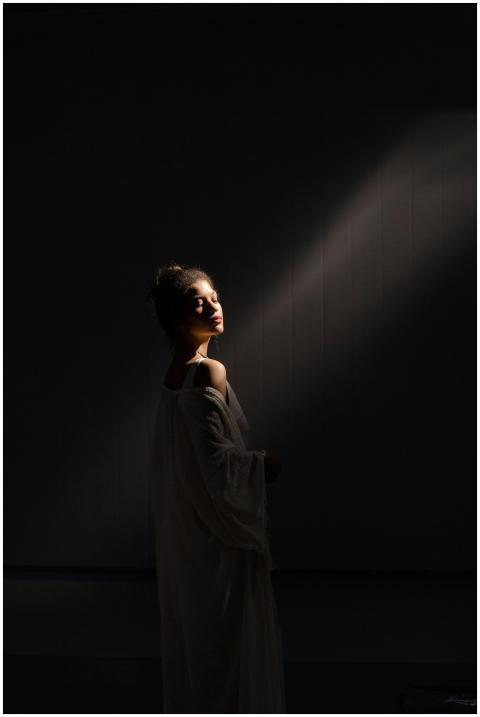 A beautiful woman standing in a spotlight wearing