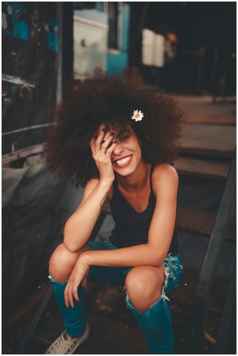 Cheerful woman wearing ripped jeans and curly hair