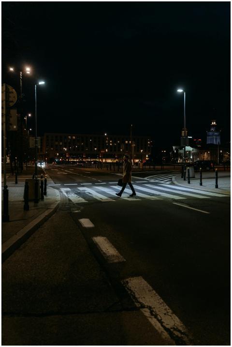 A solitary figure crosses a quiet, illuminated str