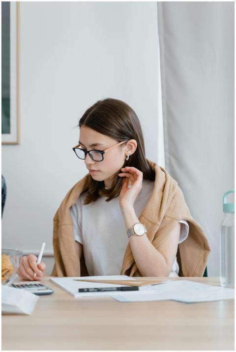 Focused young woman studying indoors, writing on p