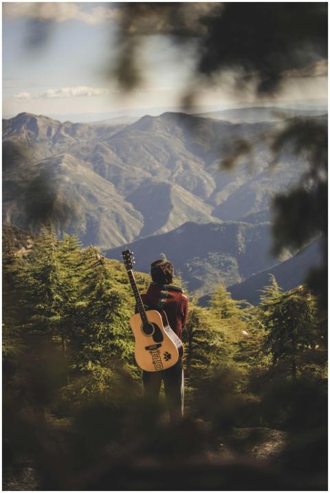 A guitarist stands in awe of the mountain scenery