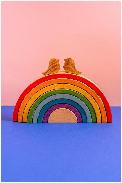 Vibrant rainbow arch topped with wooden birds on a