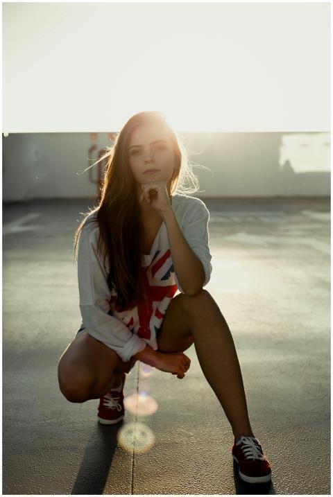 Stylish woman in casual wear squatting in sunlight