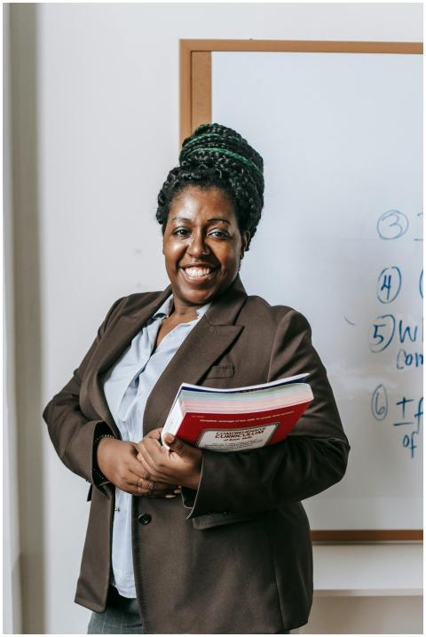 Smiling female lecturer holding books in front of