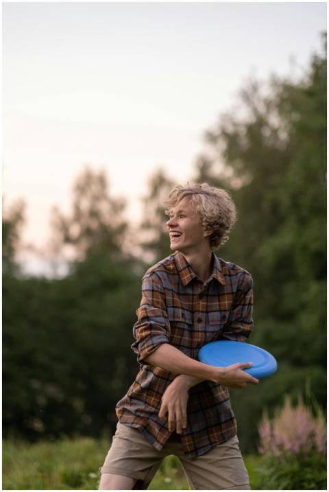 Smiling teenager plays frisbee in a sunny outdoor