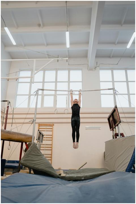 A young gymnast exercises on the uneven parallel b
