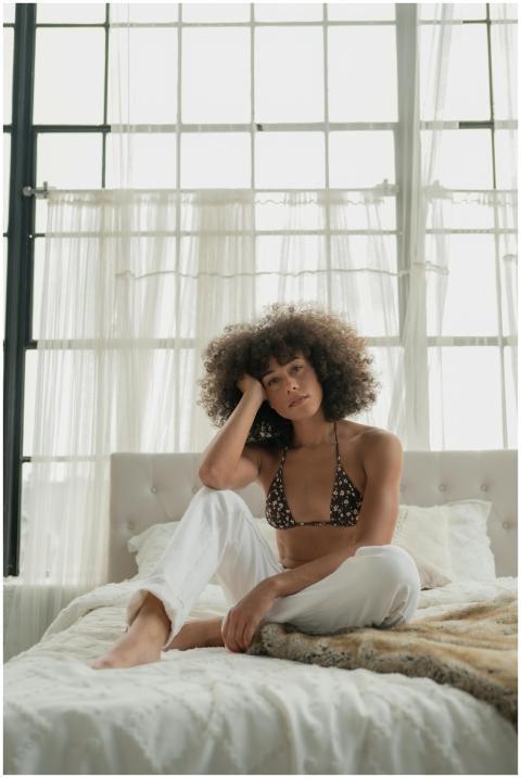 A woman with afro hair relaxing on a bed in a brig