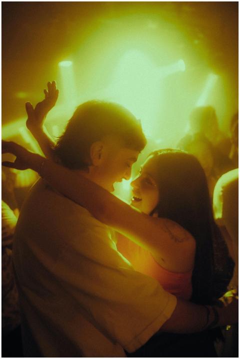 A couple lovingly embraces under vivid lights at a