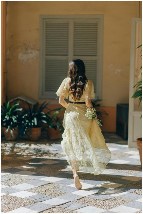 Woman in a yellow lace dress walking barefoot indo