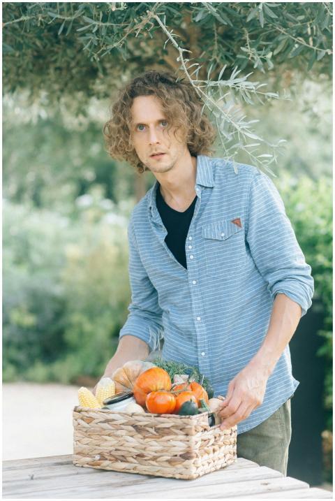 Caucasian man holds a basket of fresh produce outd