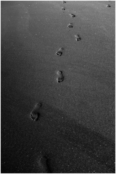 Black sand beach with footprints in monochrome, of