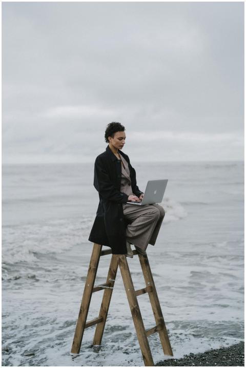 Woman sitting on a wooden ladder by the ocean, typ