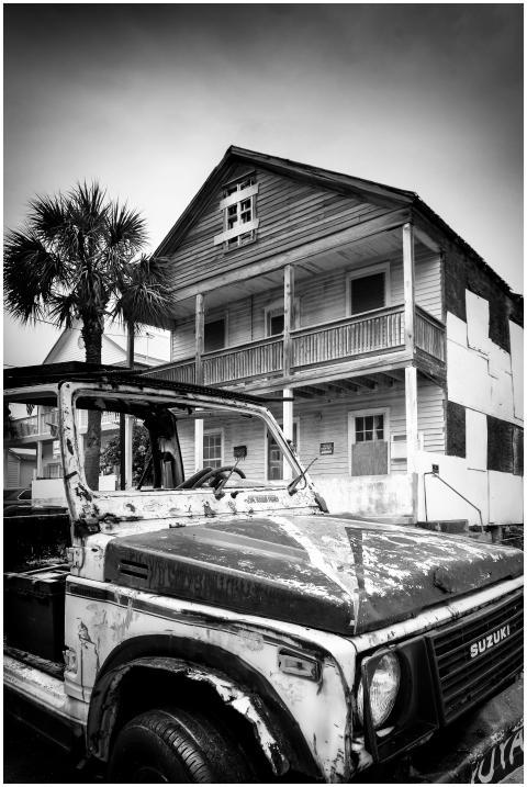 A black and white photo of an old Jeep parked in f
