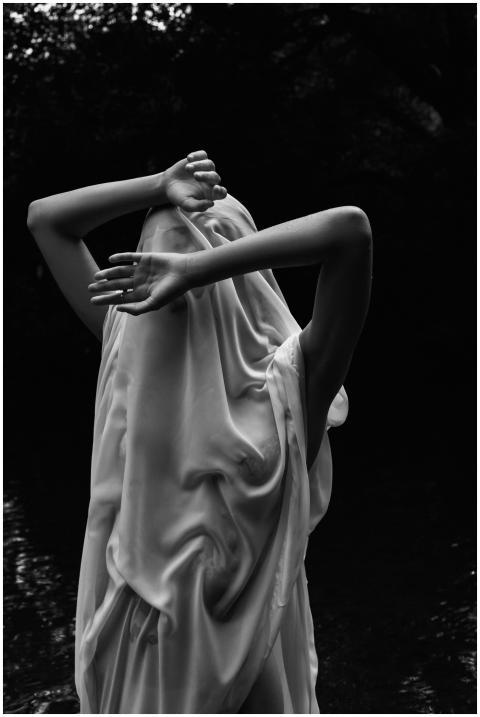 A moody black and white image of a woman in flowin