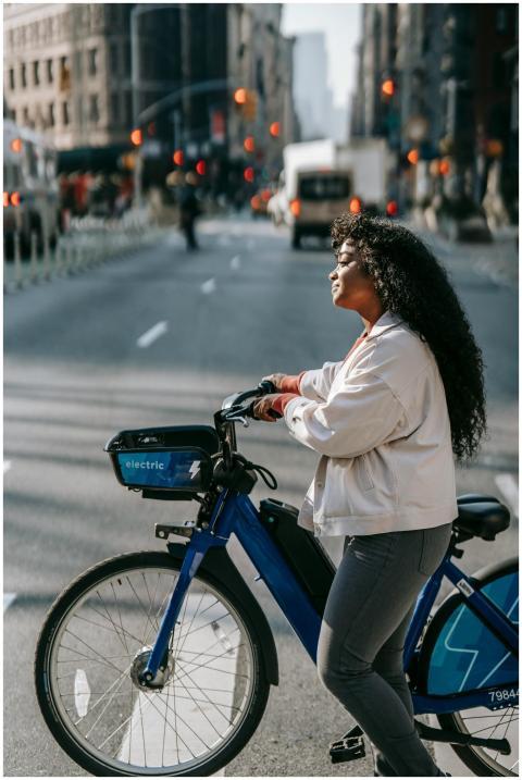 Confident young woman biking through a busy city s