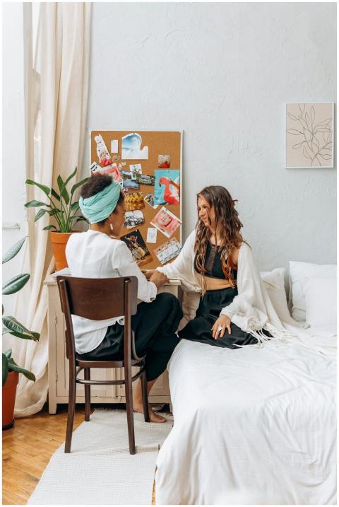 Two women sitting in a cozy bedroom having a heart