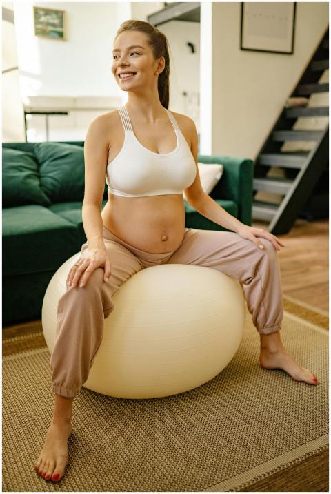 Pregnant woman sitting on exercise ball doing pren