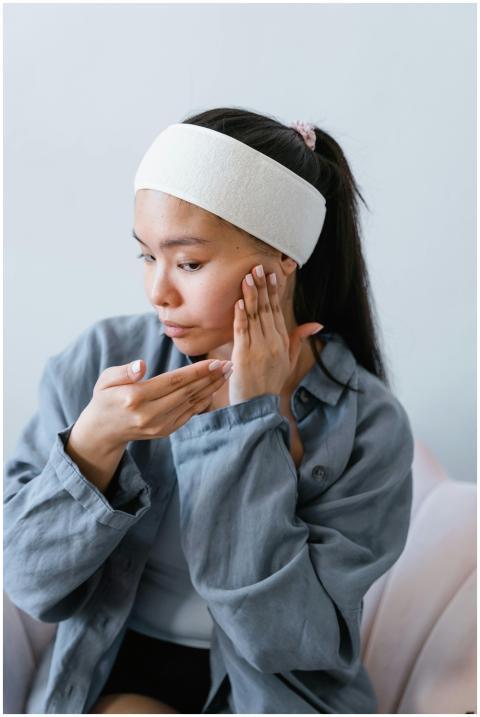 Young woman applying skincare product indoors, pro