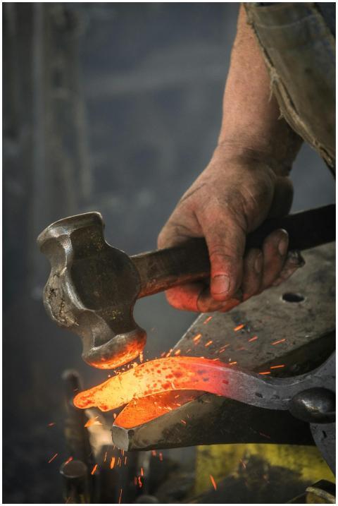 Close-up of a blacksmith hammering a hot iron piec