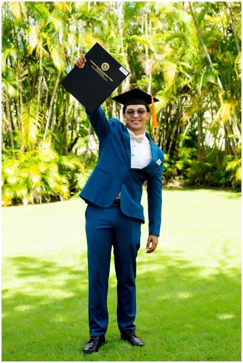 Graduate in cap and gown celebrates with diploma i