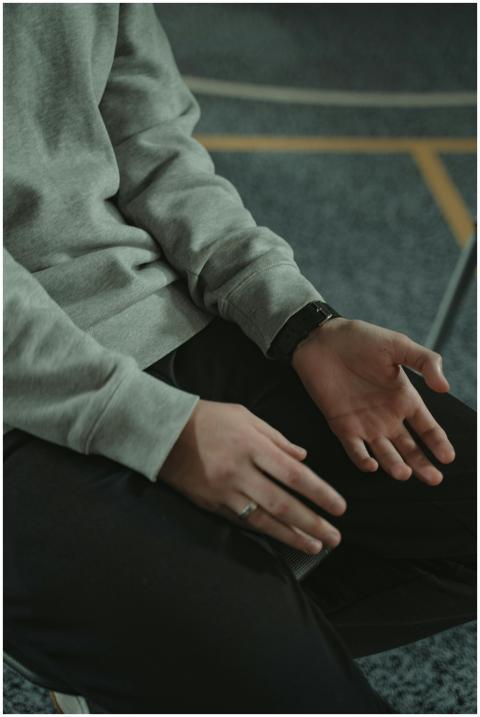 Person's hands resting thoughtfully on lap, expres
