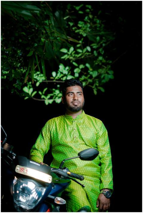 A man in vibrant traditional dress sits on a motor