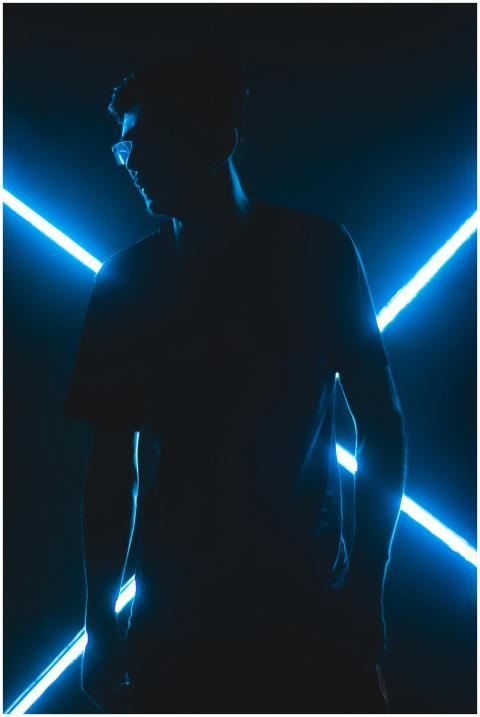 A man silhouetted against glowing blue neon lights
