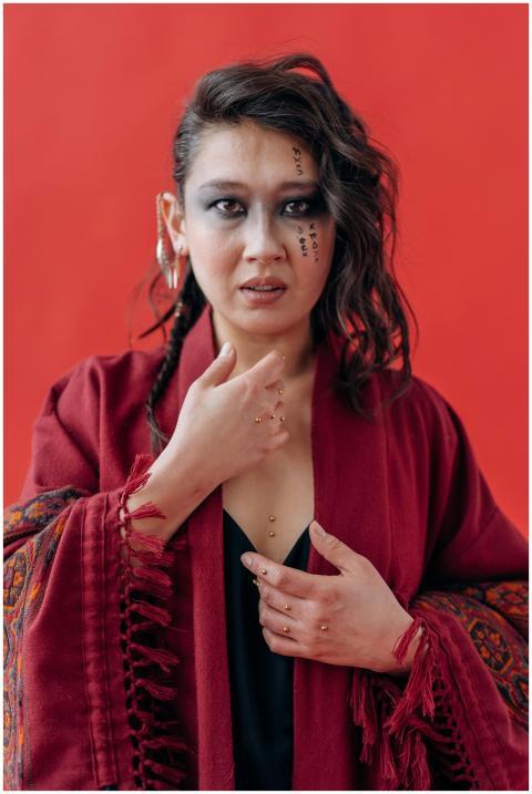 Woman in red shawl with artistic makeup poses conf