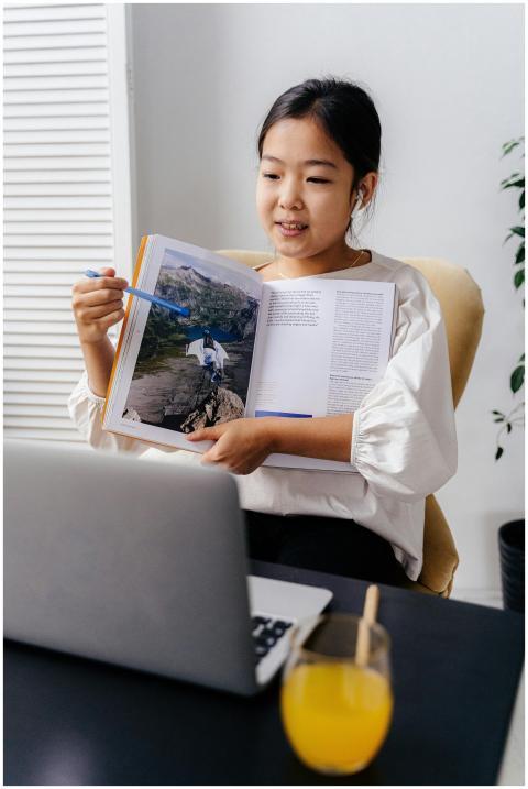 Asian girl showing an open book during a home virt