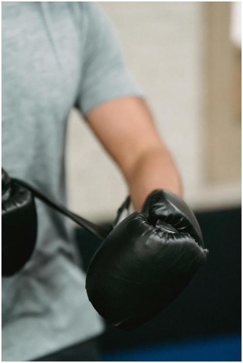 Male boxer adjusting black gloves in a gym setting