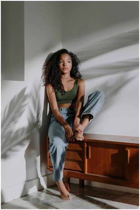 Beautiful woman sitting on a cabinet in sunlight w